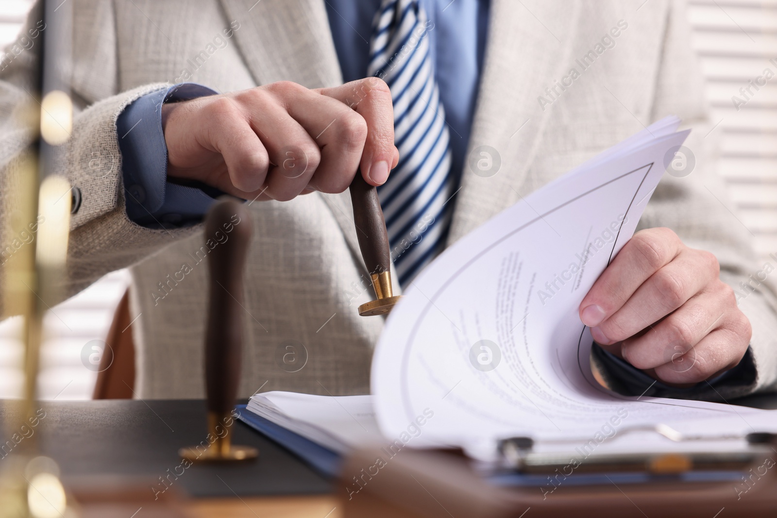 Photo of Notary stamping document at table in office, closeup