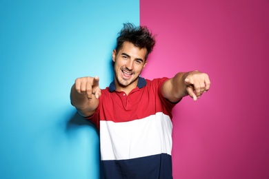 Young man with trendy hairstyle posing on color background