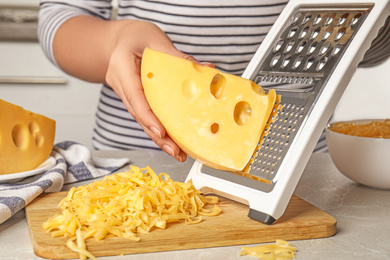 Photo of Woman grating fresh cheese at table, closeup