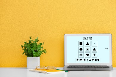 Modern laptop with IQ test on screen near yellow wall