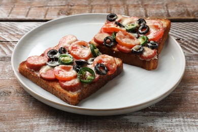 Photo of Tasty pizza toasts on wooden table, closeup