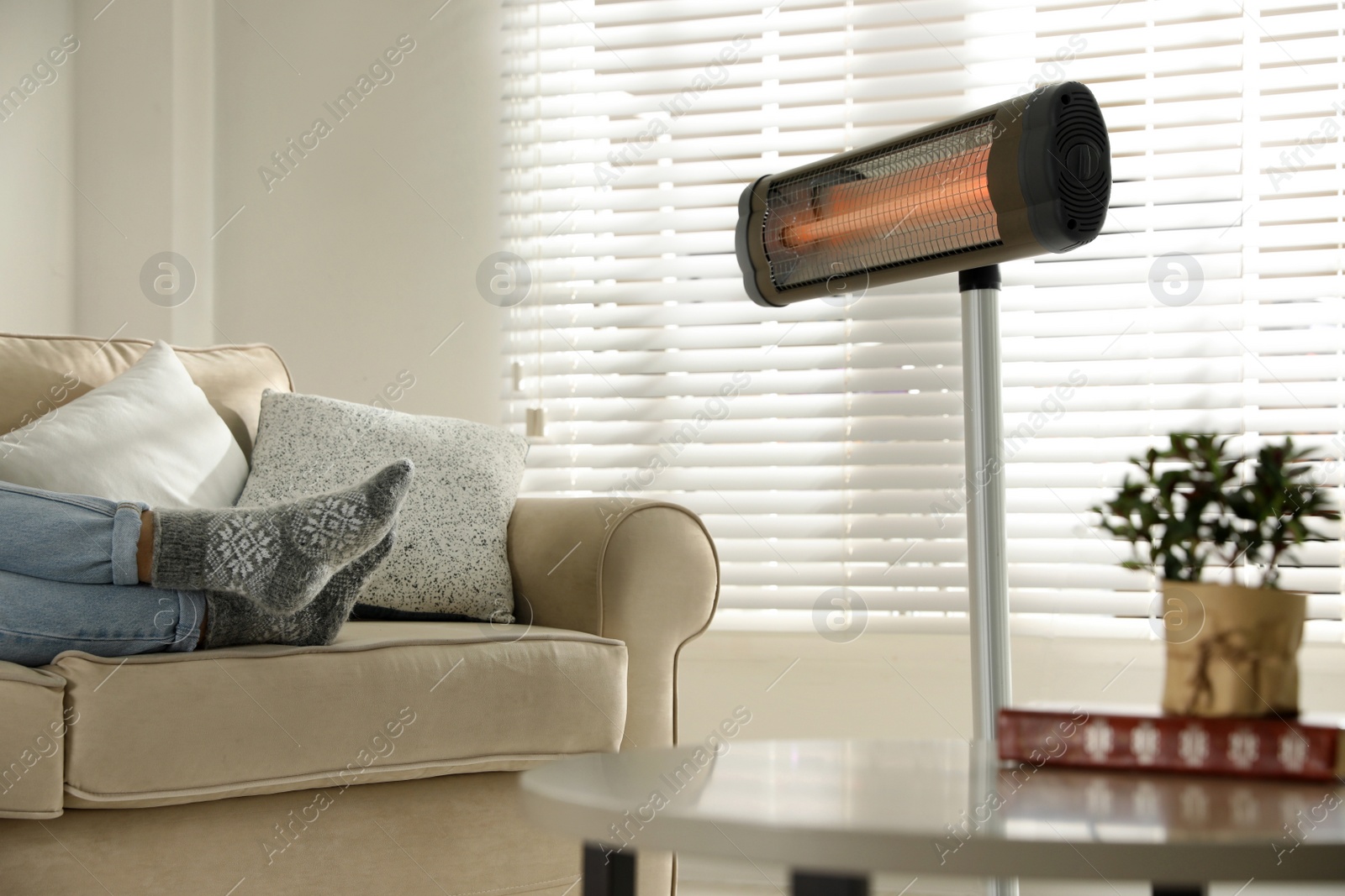 Photo of Woman near electric infrared heater in living room, closeup