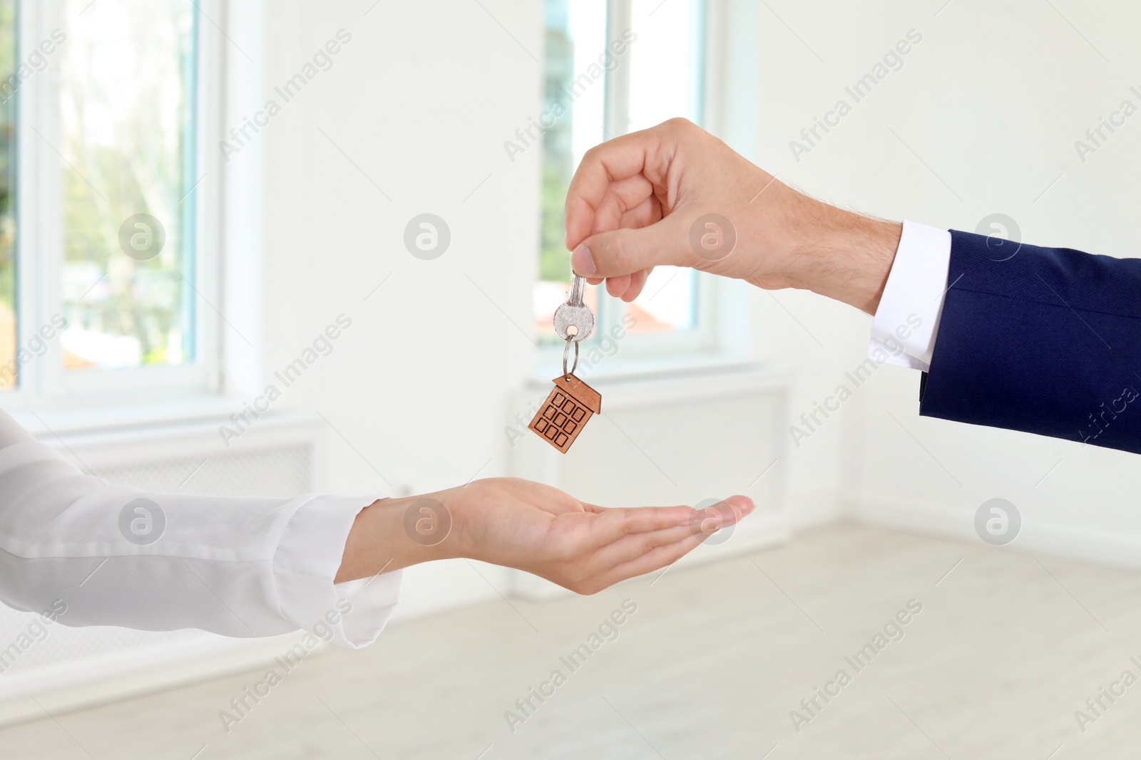 Photo of Real estate agent giving key to woman on blurred background, closeup