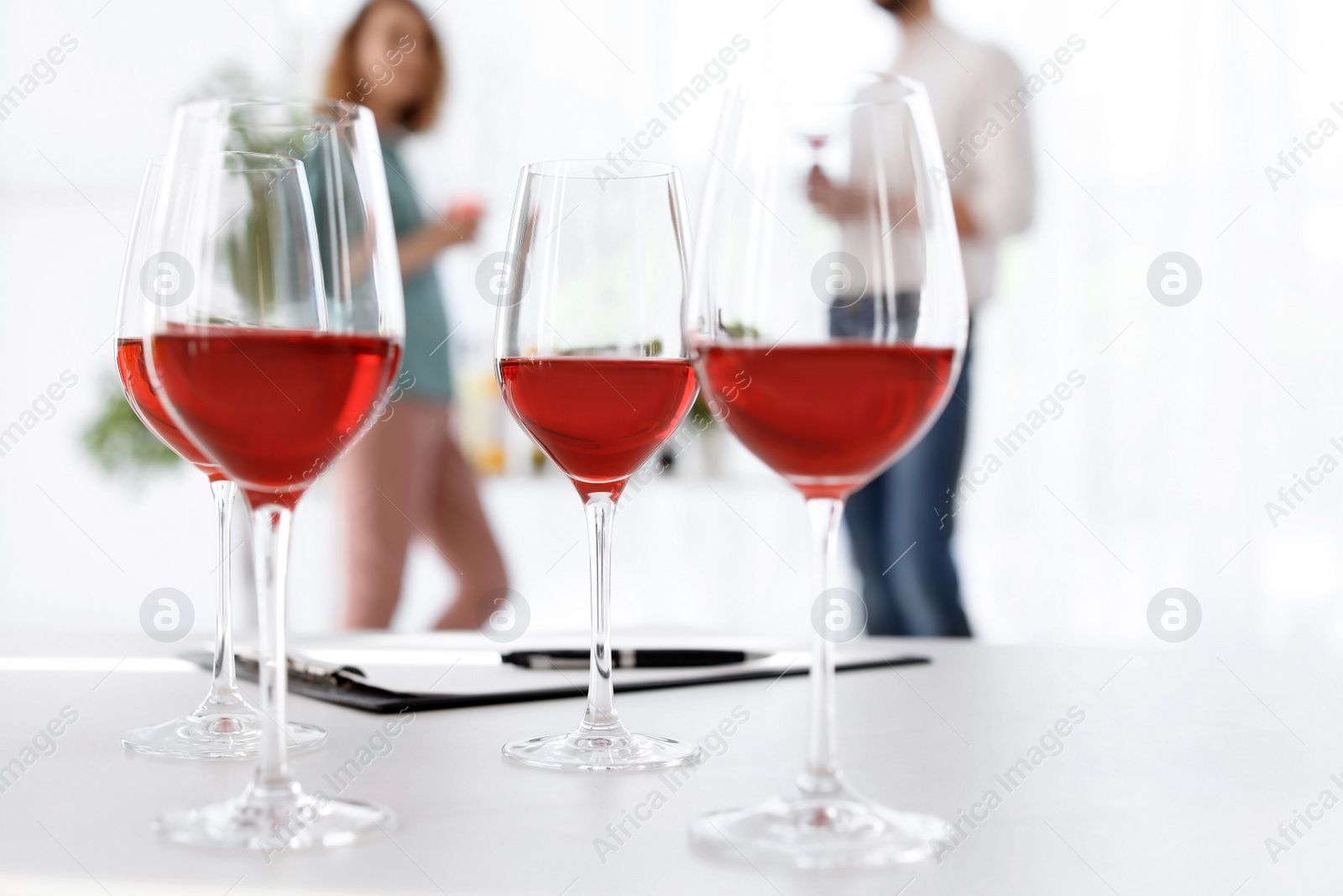 Photo of Glasses with delicious wine and blurred people on background