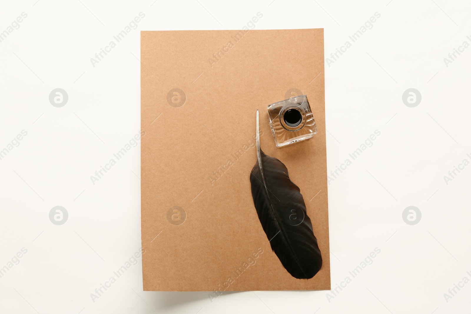 Photo of Feather pen, inkwell and sheet of paper on white background, top view. Space for text