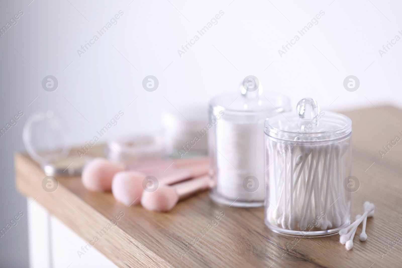 Photo of Cotton buds and pads in transparent holders on wooden table