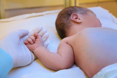Photo of Doctor holding newborn child's hand in hospital, closeup