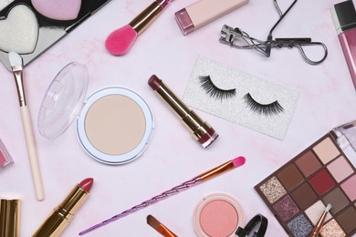 Flat lay composition with makeup products on pink marble table