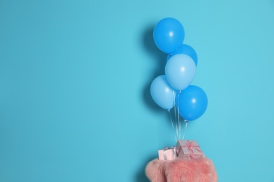 Photo of Bunch of bright balloons and gifts on table against color wall, space for text