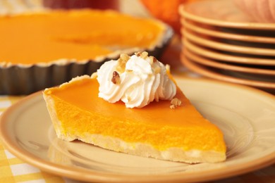 Piece of fresh homemade pumpkin pie with whipped cream on table, closeup