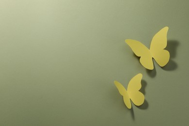 Photo of Yellow paper butterflies on pale green background, top view. Space for text