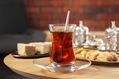 Photo of Traditional Turkish tea in glass and Eastern sweets on wooden table