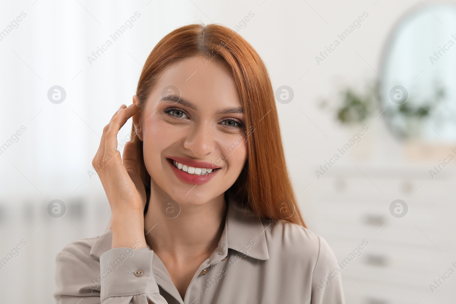 Photo of Portrait of beautiful young woman with red hair at home. Attractive lady smiling and looking into camera. Space for text