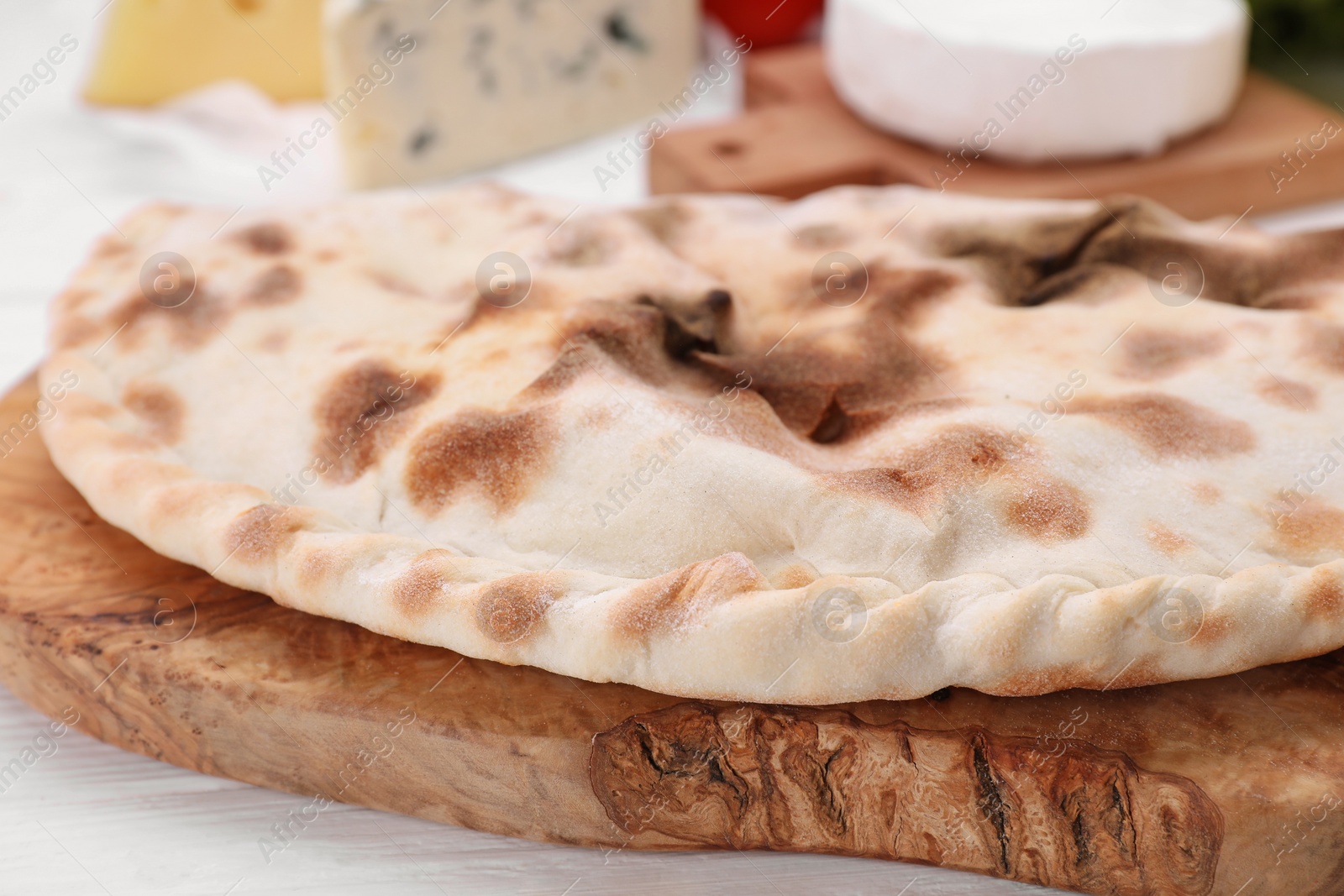 Photo of Delicious cheese calzone on white wooden table, closeup