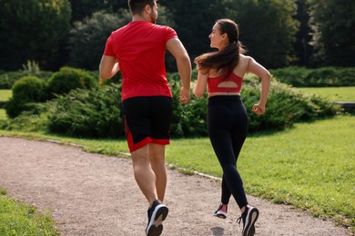 Healthy lifestyle. Couple running in park on sunny day, back view