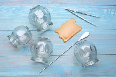 Photo of Cupping set on light blue wooden table, flat lay