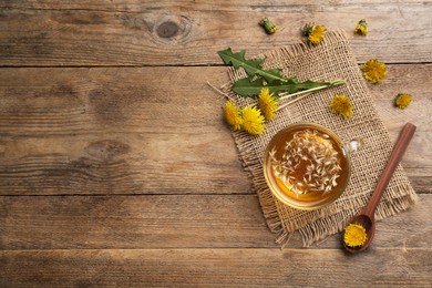 Delicious tea and dandelion flowers on wooden table, flat lay. Space for text
