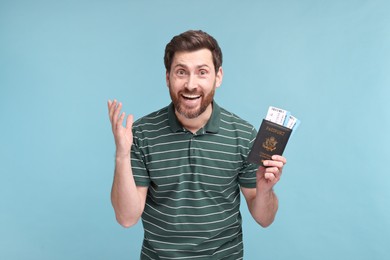 Emotional man with passport and tickets on light blue background