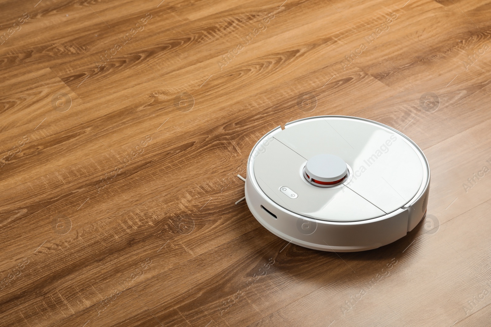 Photo of Robotic vacuum cleaner on wooden floor, space for text