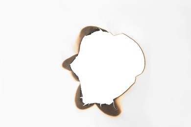 Burnt hole in paper on white background