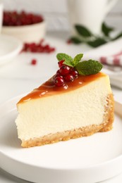 Photo of Piece of delicious caramel cheesecake with red currants and mint served on white marble table