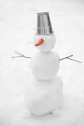 Cute snowman with metal bucket and carrot nose outdoors on winter day