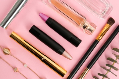 Flat lay composition with bright lipsticks and accessories on pink background