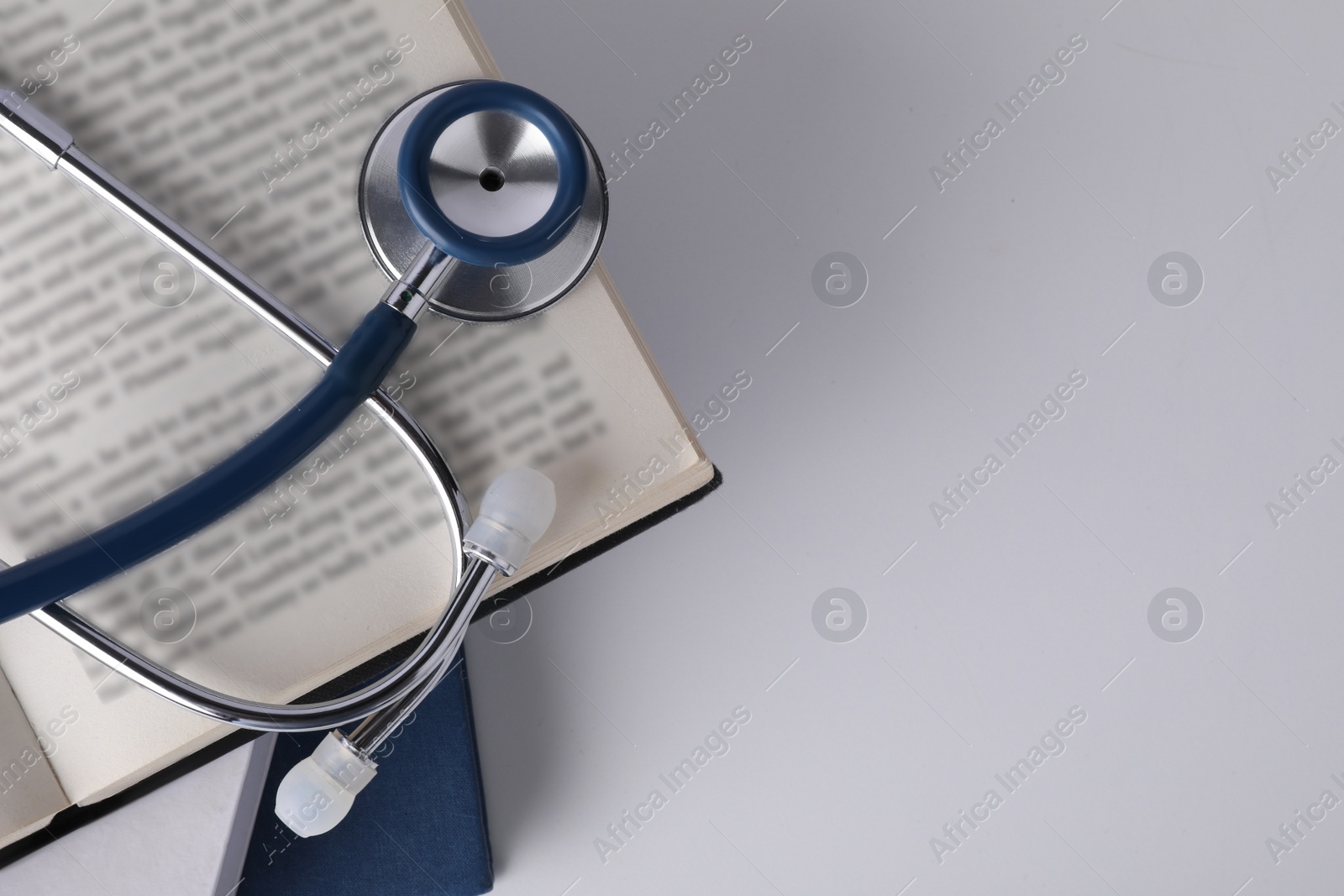 Photo of Open student textbook and stethoscope on white background, top view. Medical education