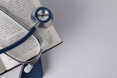 Photo of Open student textbook and stethoscope on white background, top view. Medical education