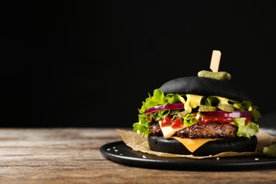 Photo of Slate plate with black burger on table. Space for text