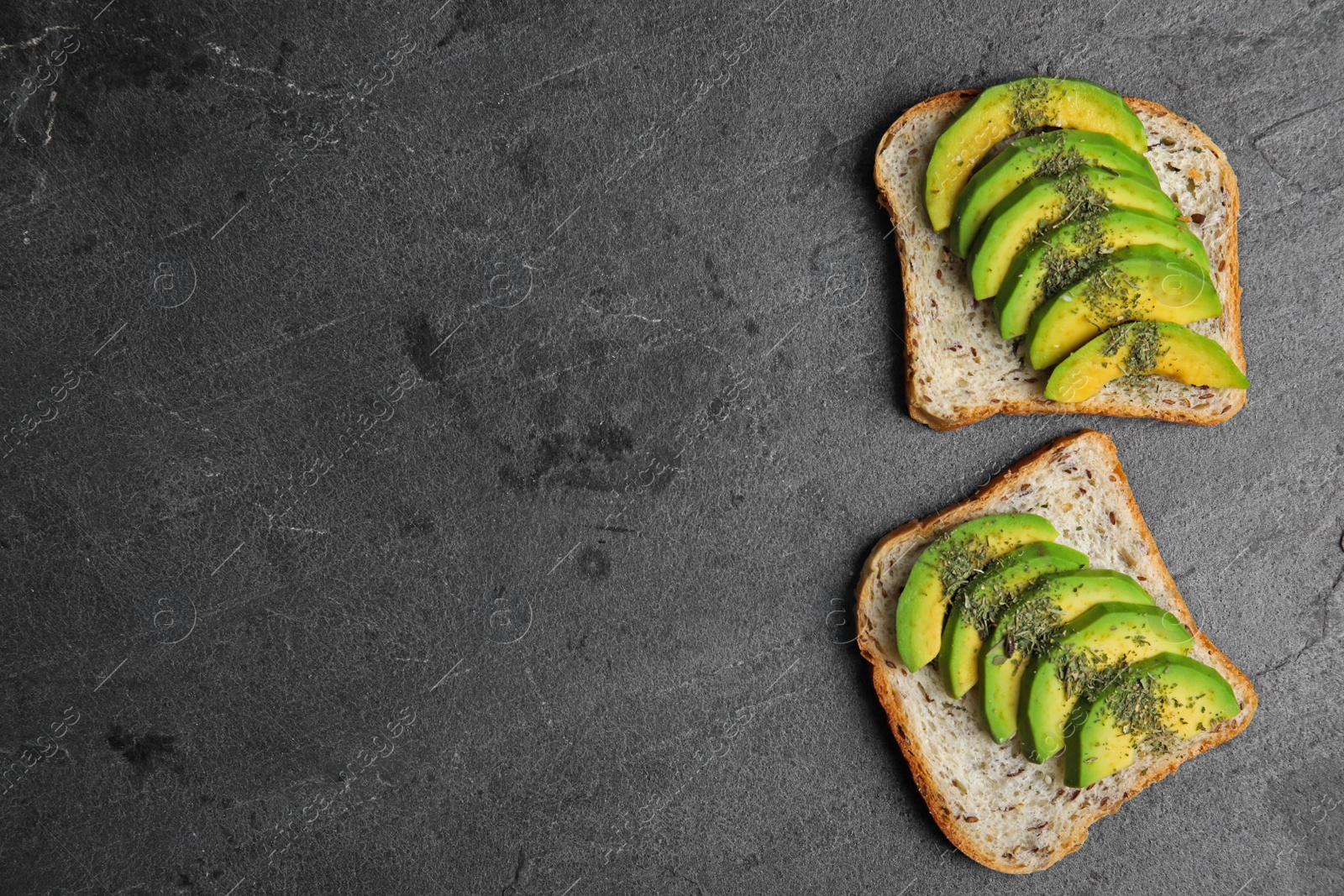 Photo of Tasty toasts with avocado on black table, flat lay. Space for text