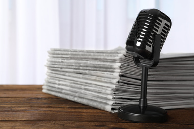 Photo of Newspapers and vintage microphone on wooden table. Journalist's work