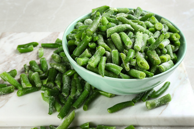 Photo of Frozen green beans on light grey marble table, closeup. Vegetable preservation