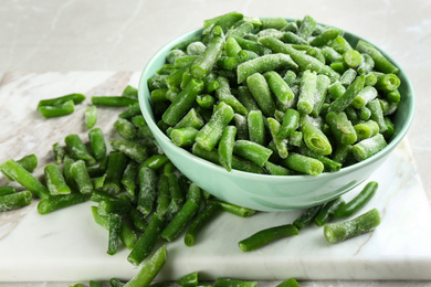 Frozen green beans on light grey marble table, closeup. Vegetable preservation