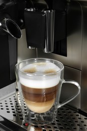 Modern coffee machine with glass cup of latte, closeup