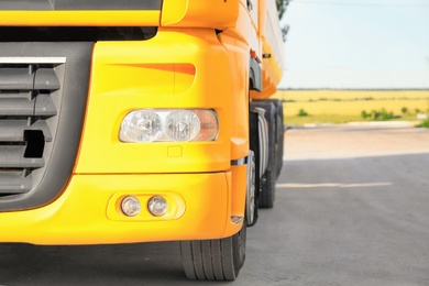 Photo of Modern yellow truck parked on country road, closeup. Space for text