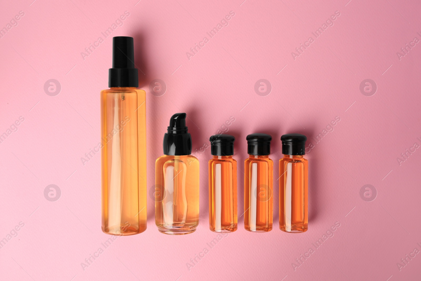 Photo of Bottles of cosmetic products on pink background, flat lay