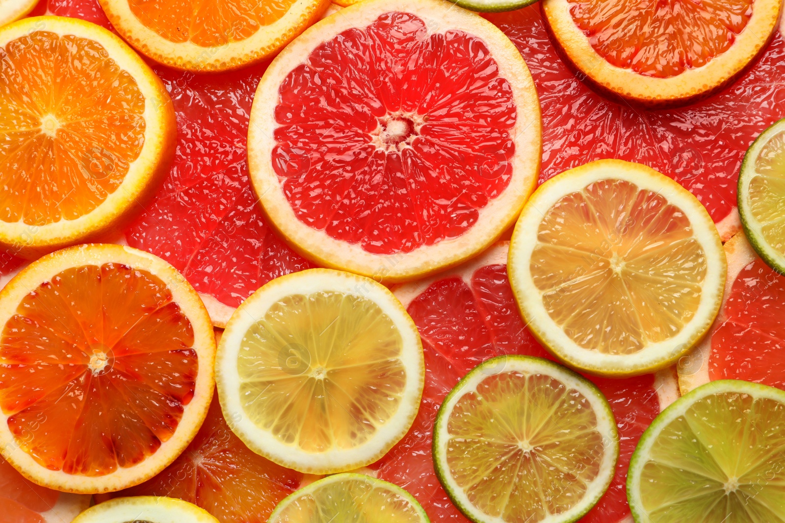 Photo of Slices of fresh citrus fruits as background, top view