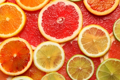 Photo of Slices of fresh citrus fruits as background, top view