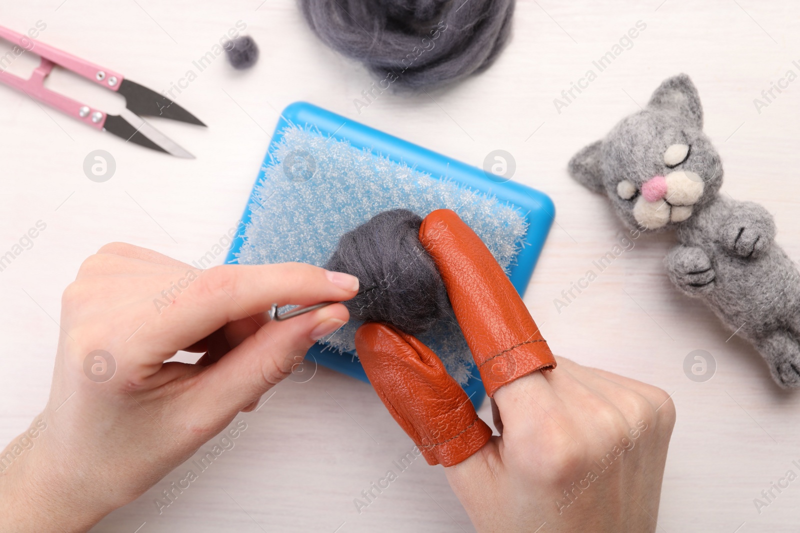 Photo of Woman felting from wool at light wooden table, top view