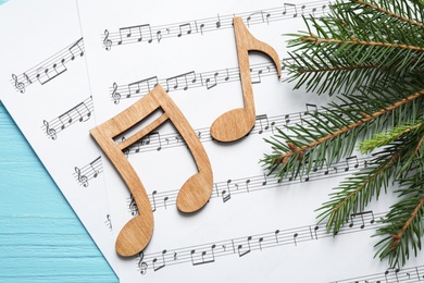 Christmas tree branch, notes and music sheets on blue wooden table, flat lay