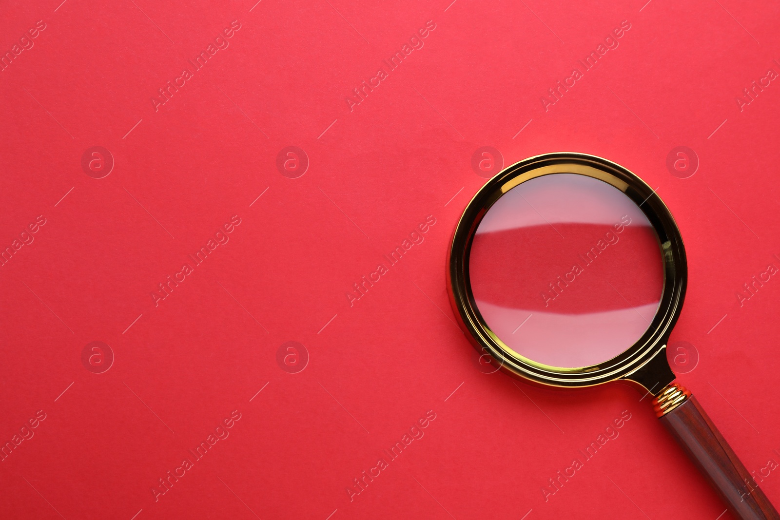 Photo of Magnifying glass on red background, top view. Space for text