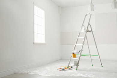 Photo of Stepladder and different tools in room. Interior renovation