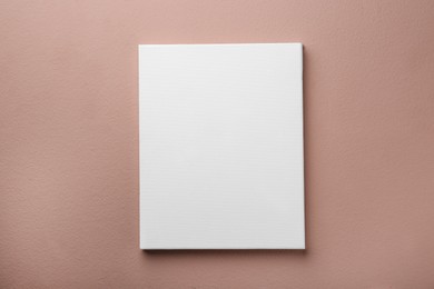 Photo of Blank canvas on pale pink wall. Space for design