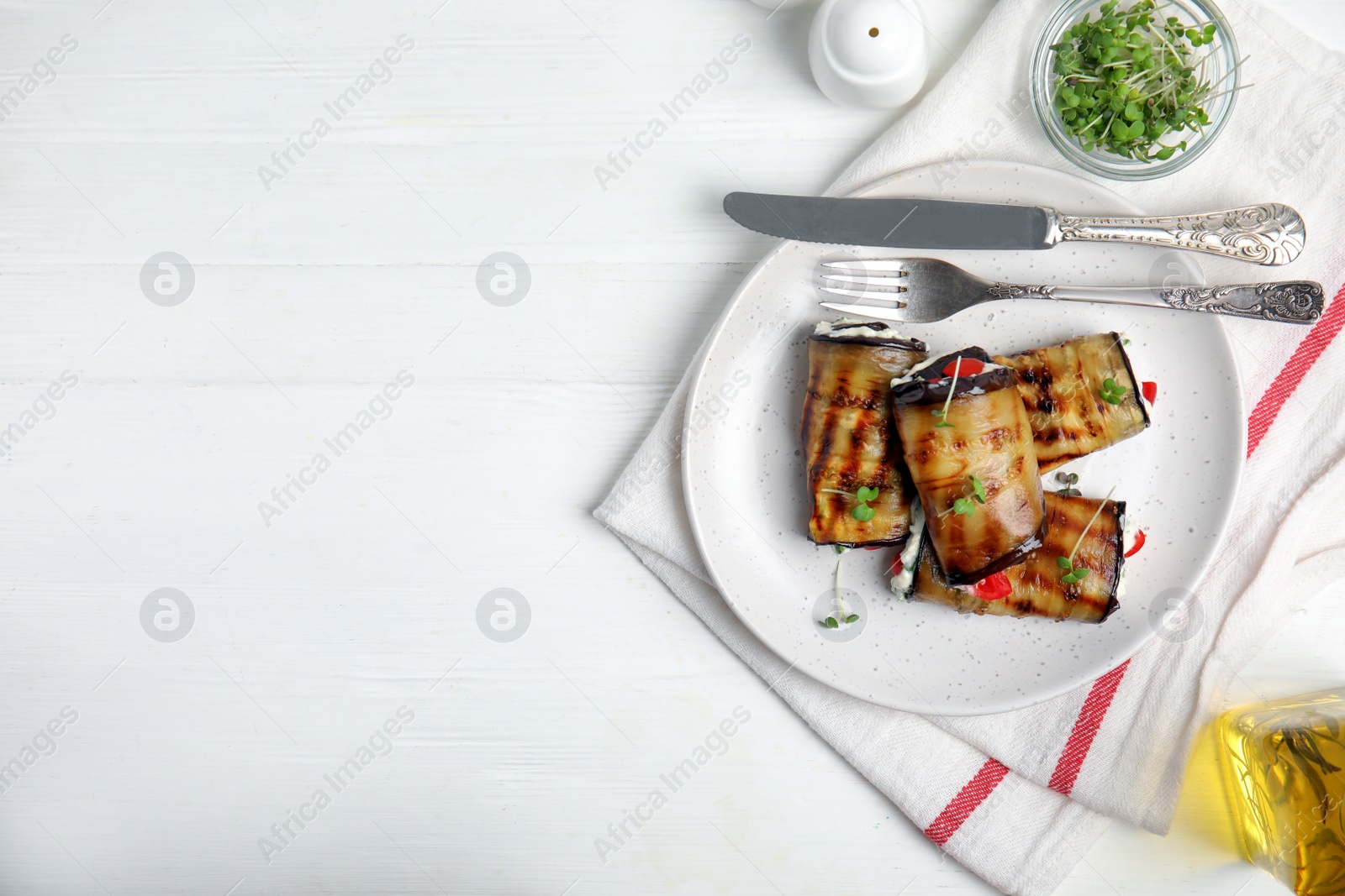 Photo of Delicious baked eggplant rolls served on white wooden table, flat lay. Space for text