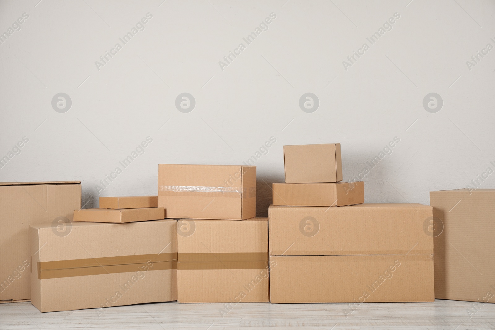 Photo of Pile of cardboard boxes near light wall indoors