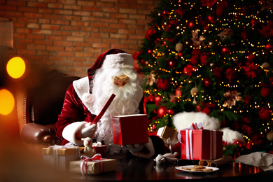 Santa Claus with gifts near Christmas tree