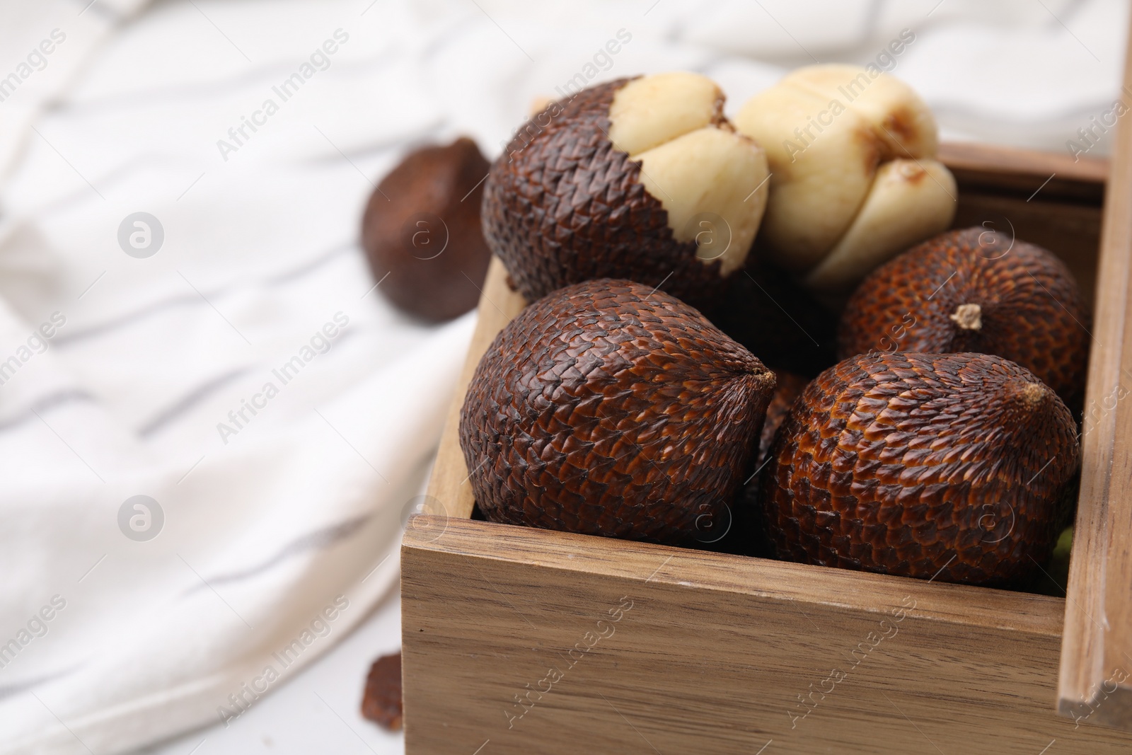Photo of Wooden crate with fresh salak fruits on table, closeup. Space for text