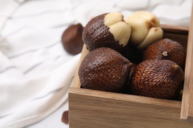 Photo of Wooden crate with fresh salak fruits on table, closeup. Space for text