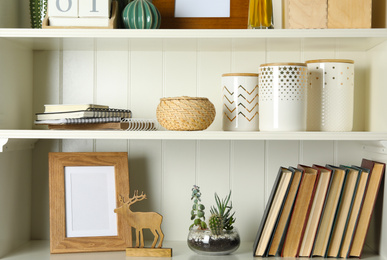 Photo of White shelving unit with books and different decorative elements